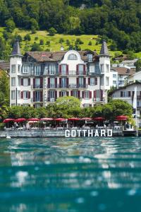 a large building with red umbrellas in front of the water at Seehotel Gotthard in Weggis