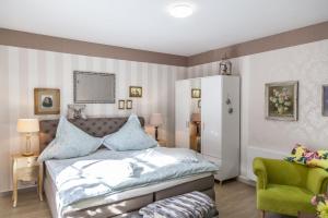 a bedroom with a bed and a green chair at Sonnenhof Plauen in Plauen