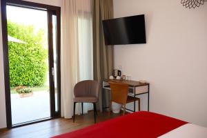 a bedroom with a table and a desk with a television at Elaia Rooms in Noto Marina