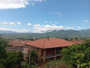 a house with a red roof with mountains in the background at Appartamento vacanza Penne in Penne
