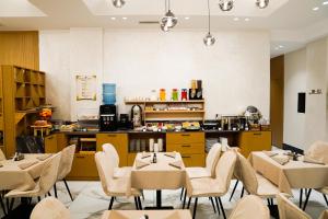 a restaurant with tables and chairs and a kitchen at Nayel Hotel in Durrës