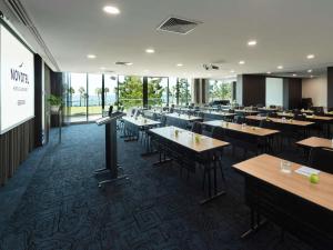 a dining room with tables and chairs and windows at Novotel Geelong in Geelong