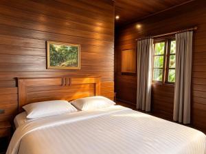 a bedroom with a bed with wooden walls and a window at KTM Resort Batam in Sekupang +61 photos