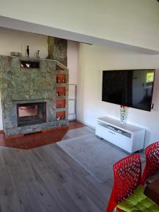 a living room with a stone fireplace and a flat screen tv at Chalupa u Záhradníkov in Trebostovo