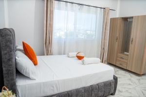a bedroom with a bed with orange pillows and a window at Malindi White in Malindi