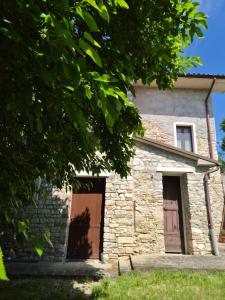 a stone house with two doors and a tree at Agriturismo Vallonga in Poggio San Vicino