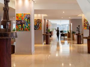 a person walking down a hallway with paintings on the walls at Pullman Kinshasa Grand Hotel in Kinshasa +241 photos