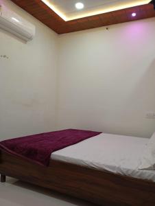 a bed in a white room with at Ashish Aram Ghar in Ujjain