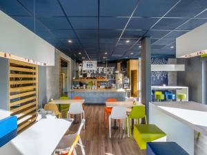 a restaurant with blue ceilings and tables and chairs at ibis budget Pau Lescar in Lescar