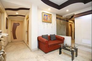 a living room with a red couch and a table at Hotel Rushabh Home in Kolkata