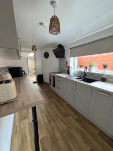 a kitchen with white cabinets and a large window at Gladstone Getaway in Peterhead