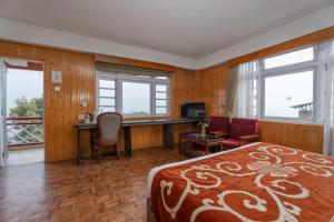 a bedroom with a bed and a desk with a computer at Summit Tashi Ghang Heritage Resort in Pelling