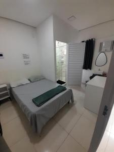 a white bedroom with a bed and a window at Hostel e Pousada Garanhuns in Garanhuns