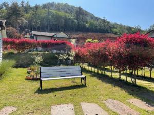 a park bench sitting in the grass near flowers at Wando Haegeum Pension in Wando