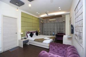 a bedroom with a bed and a purple couch at Hotel Rushabh Home in Kolkata