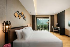 a bedroom with a large white bed and a desk at Amari Vang Vieng in Vang Vieng