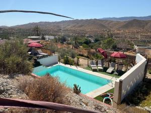a swimming pool with chairs and umbrellas on top of a house at Finca Indalopez in Tabernas