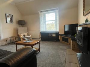 a living room with a couch and a tv at Dun-Niall Apartment in Oban +3 photos