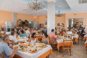Eine Gruppe von Menschen sitzt an Tischen in einem Restaurant in der Unterkunft Hotel Jasmine Beach in Rimini