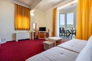 a hotel room with a white bed and a desk and a window at Hotel Adria in Neum