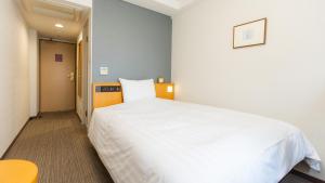 a bedroom with a large white bed and a table at Richmond Hotel Sapporo Ekimae in Sapporo