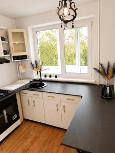 a kitchen with white cabinets and a black counter top at Romance Apartments in Panevėžys