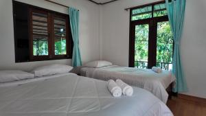two beds in a room with two windows at Sanfhan Resort-SHA Plus in Khao Chai Son