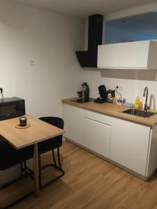 a kitchen with white cabinets and a wooden table at Chambre Standing Ruffec avec Air Climatisé in Ruffec