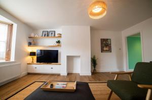 a living room with a couch and a tv at High Street Retreat in Whitstable