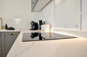 a white kitchen with a coffee maker on a counter at High Street Retreat in Whitstable +36 photos
