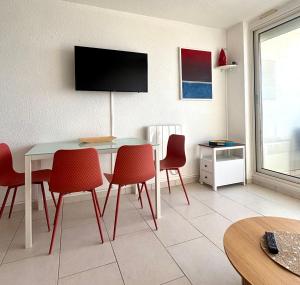 a dining room with a table and red chairs at Le Grand Large - T2 vue océan in Mimizan-Plage