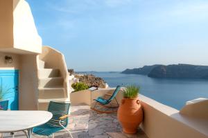 a balcony with a table and chairs and the ocean at Nano Oia Villas in Oia