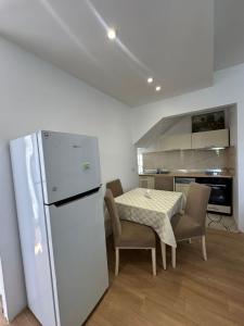 a kitchen with a white refrigerator and a table and chairs at Vila Nela in Shkodër