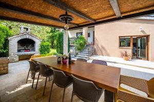 an outdoor patio with a wooden table and a fireplace at Villa Ferlini in Central Istria with private 10000 m2 garden, wellness & family activities on plot in Svetvinčenat
