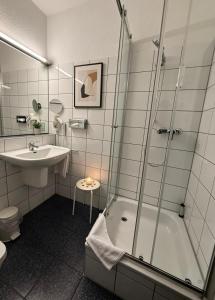 a bathroom with a shower and a tub and a sink at Hotel Goldener Adler in Bautzen