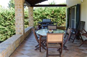 a patio with a table and chairs and a grill at Melpo Estate Kapandriti in Mikrokhórion
