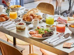 a table with plates of breakfast food on it at Boutet Bastille Hotel Paris - MGallery Collection in Paris