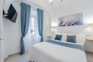 a white bedroom with a large bed with blue curtains at Domus Almaré in Minori