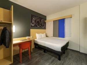 a small room with a bed and a desk and a bed sidx sidx at Ibis Queretaro in Querétaro