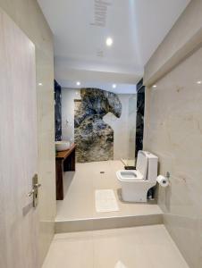 a bathroom with a toilet and a stone wall at Madalenas B&B in Pelekas +59 photos