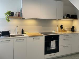 a kitchen with white cabinets and a black oven at Apt Es Poal - Des Puig in Cadaqués +2 photos