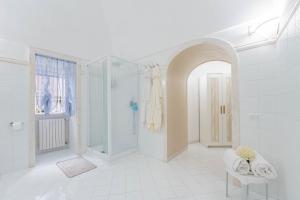 a white bathroom with a shower and a glass door at Domus Almaré in Minori +40 photos