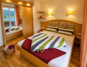 a bedroom with a large bed and a mirror at Der Kaerntnerhof am Weissensee, SeeHotel & SeeApartments direkt am See in Weissensee