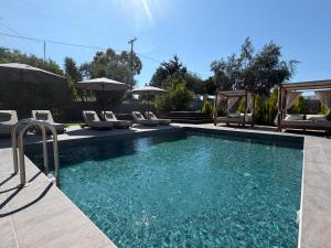 a swimming pool with chairs and umbrellas at S&T VILLA in Haraki