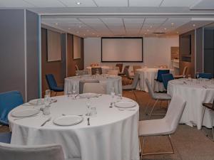 a conference room with white tables and chairs and a screen at ibis Lima Reducto Miraflores in Lima