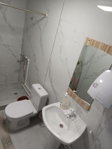 a white bathroom with a toilet and a sink at " UMAR " Guest house in Tong