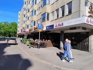 two people walking down a street in front of a building at Avenyn Hostel, former Le Mat in Gothenburg