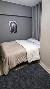 a bedroom with a bed with a white blanket at Jams Hostel - Pousada em Catalão in Catalão