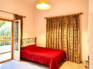 a bedroom with a red bed and a window at Spacious Mountain House In Sehayleh in Ḩayy ash Shabbūq