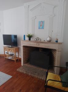 a living room with a fireplace and a television at Au Coin Maison in Ruffec